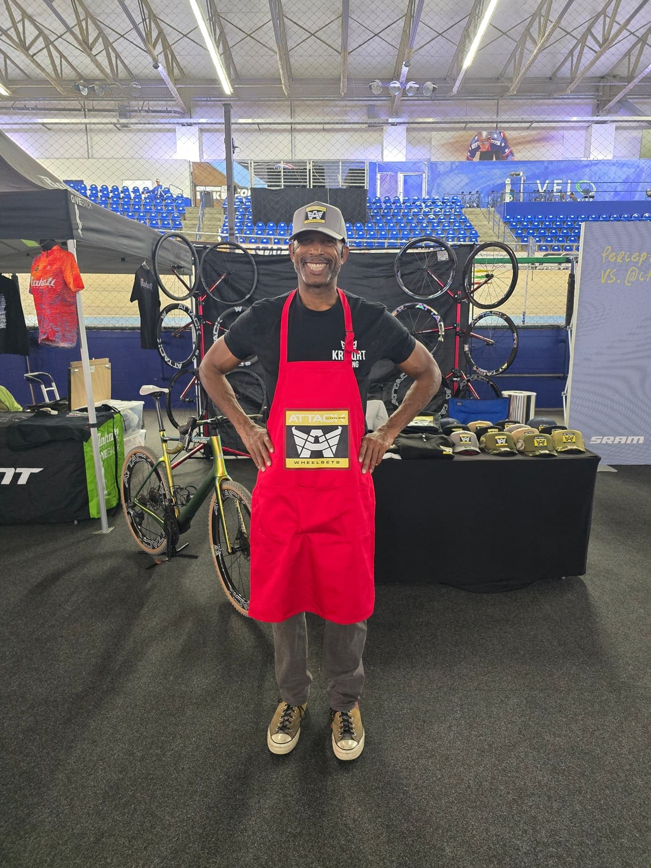 Gregory Freeman in an ATTACKCYCLES apron at his trade show booth, wheels racked behind him.