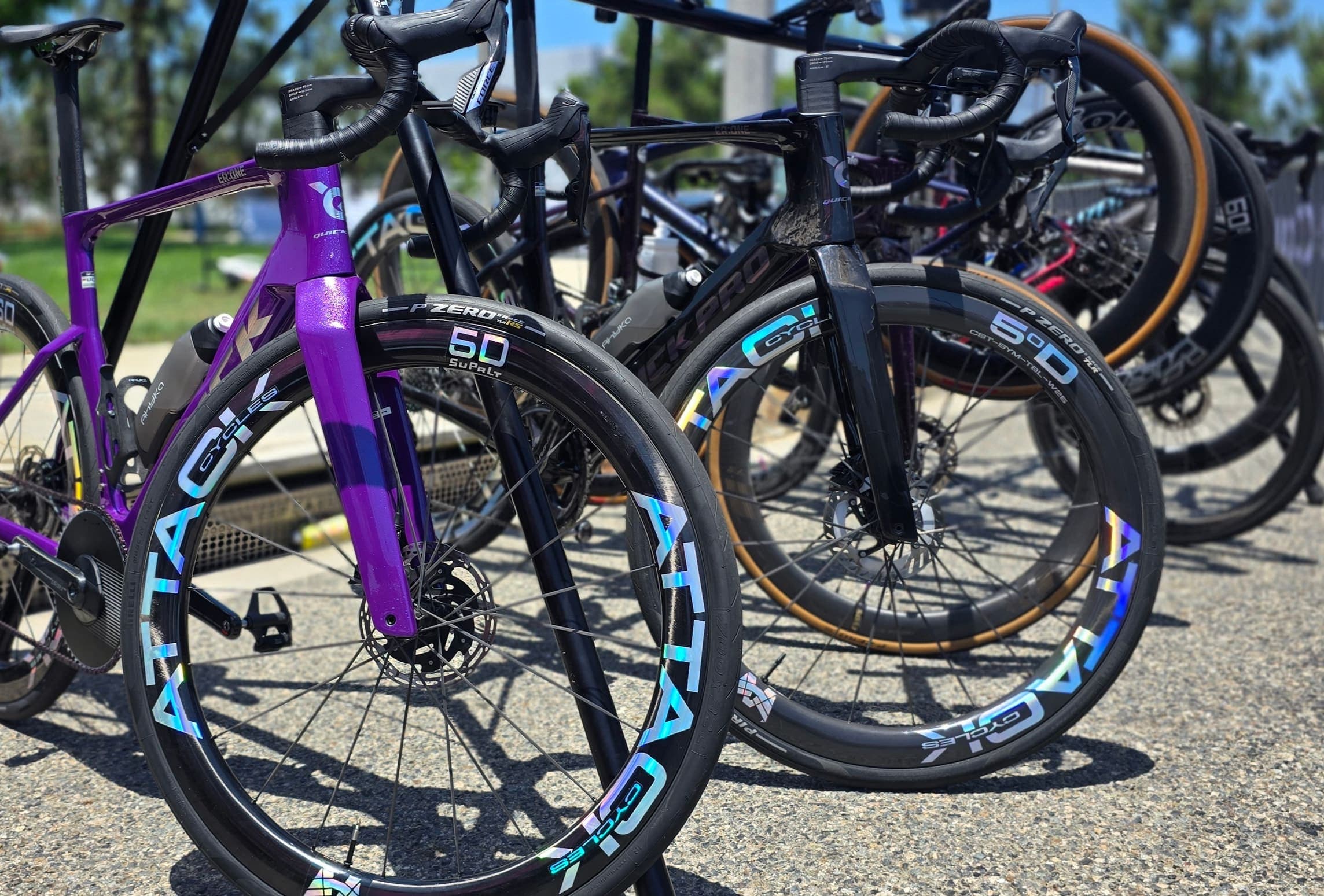 A row of bikes racked at a race, all on ATTACKCYCLES SuPrLt carbon wheels.